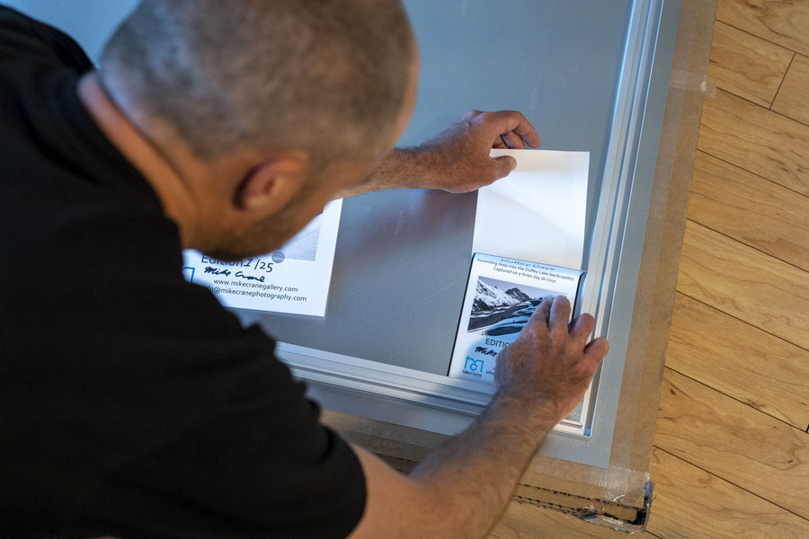 Mike Crane fitting a print into its frame in the studio