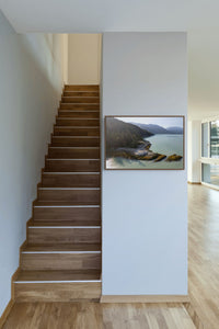 Howe Sound Passage print hanging beside a wooden staircase