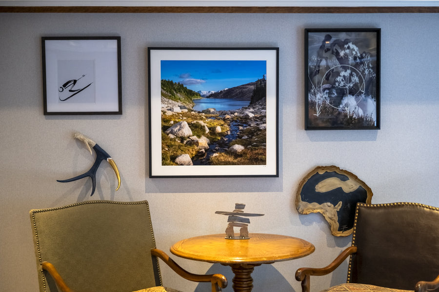 Three framed Mike Crane prints above a reading nook with leather chairs