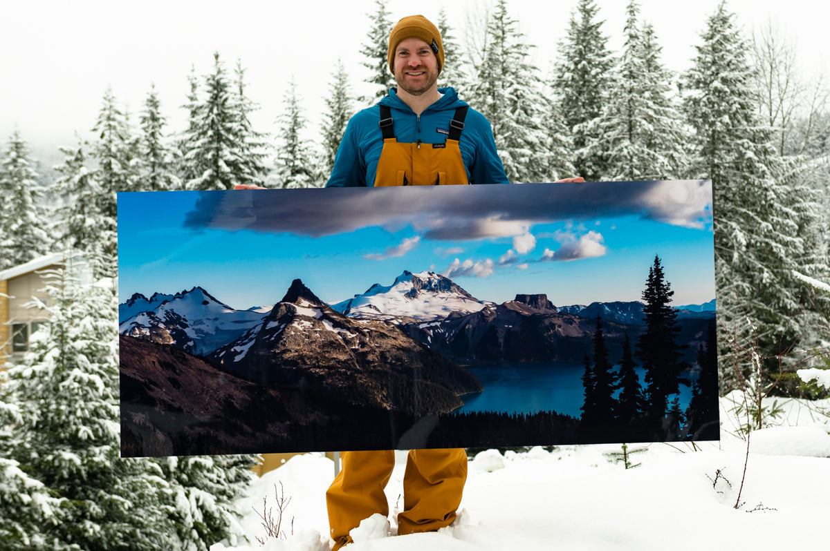 Mike Crane in the snow holding a mountain panorama print wider than his arm span